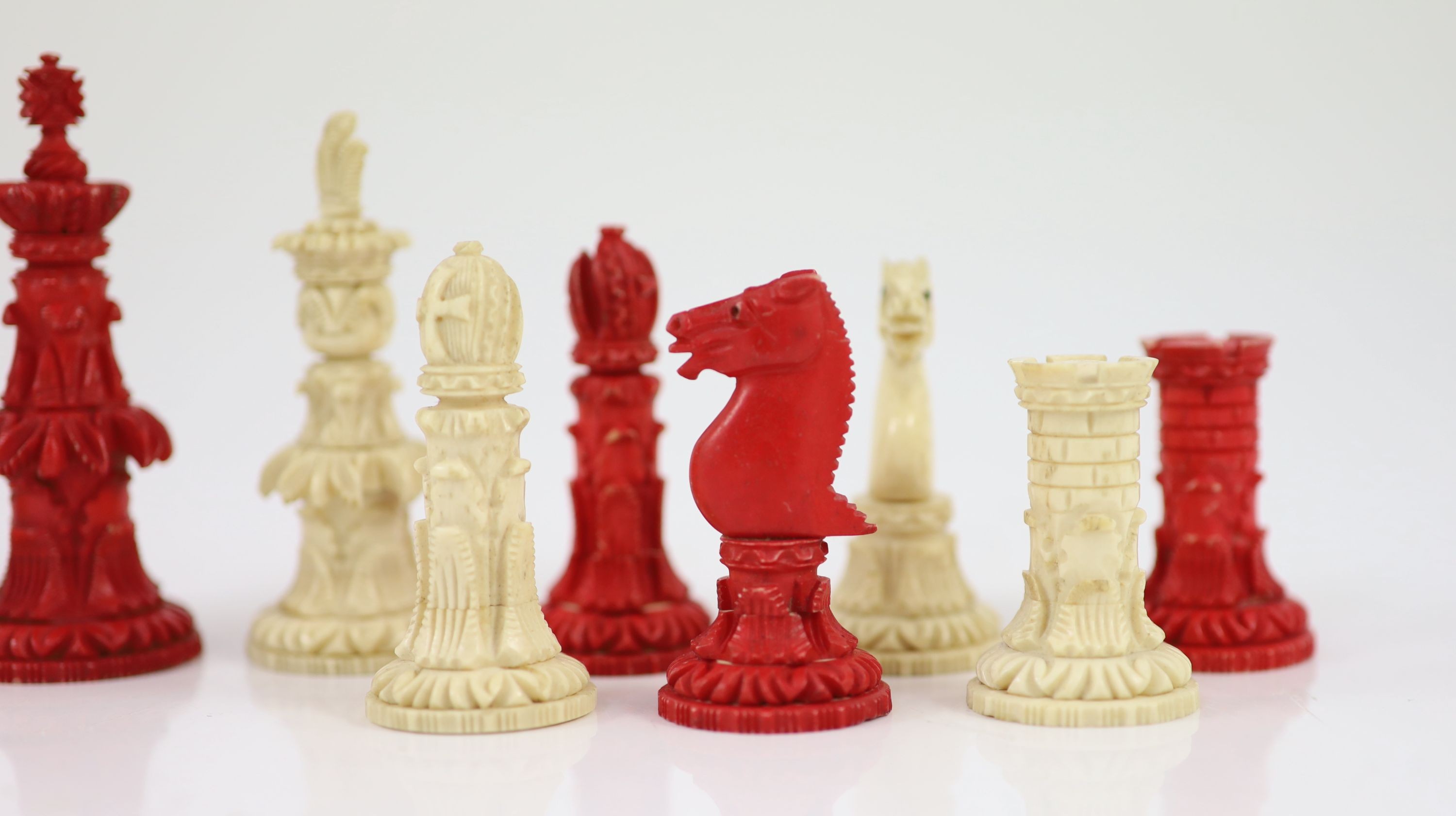 A 19th century Anglo-Indian white and stained bone chess set, with unusual carved palmate decoration, Kings 9.5cm.